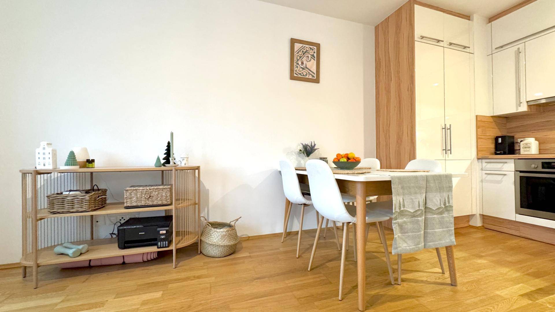 Gemütlicher Essbereich mit Holztisch und Stühlen, angrenzend an die moderne Küche mit Stauraum.