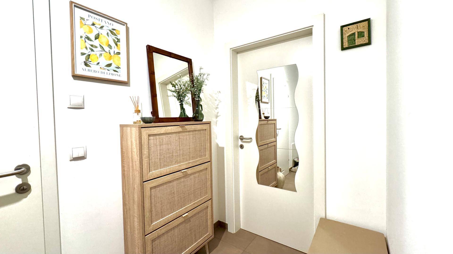 Einladender Flur mit Schuhschrank, dekorativem Spiegel und hellem Fliesenboden.