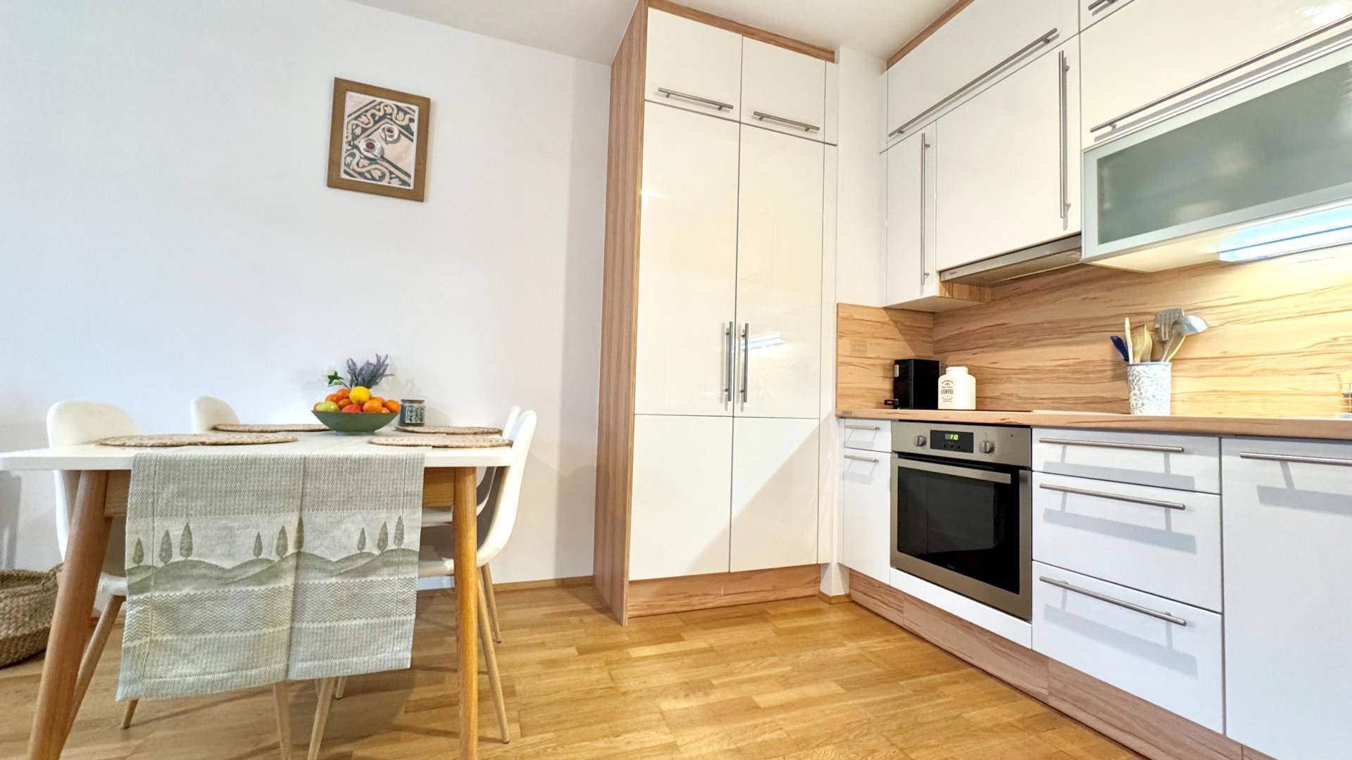Helle Küche mit Essbereich, weißen Schränken und Holzarbeitsplatte, ideal für gemeinsame Mahlzeiten.