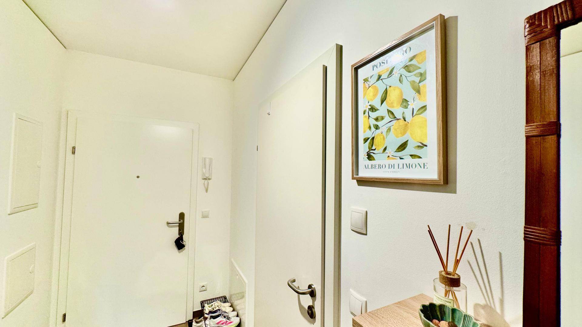 Eingangsbereich mit heller Tür, Gegensprechanlage und schlichtem Design, funktional und einladend.