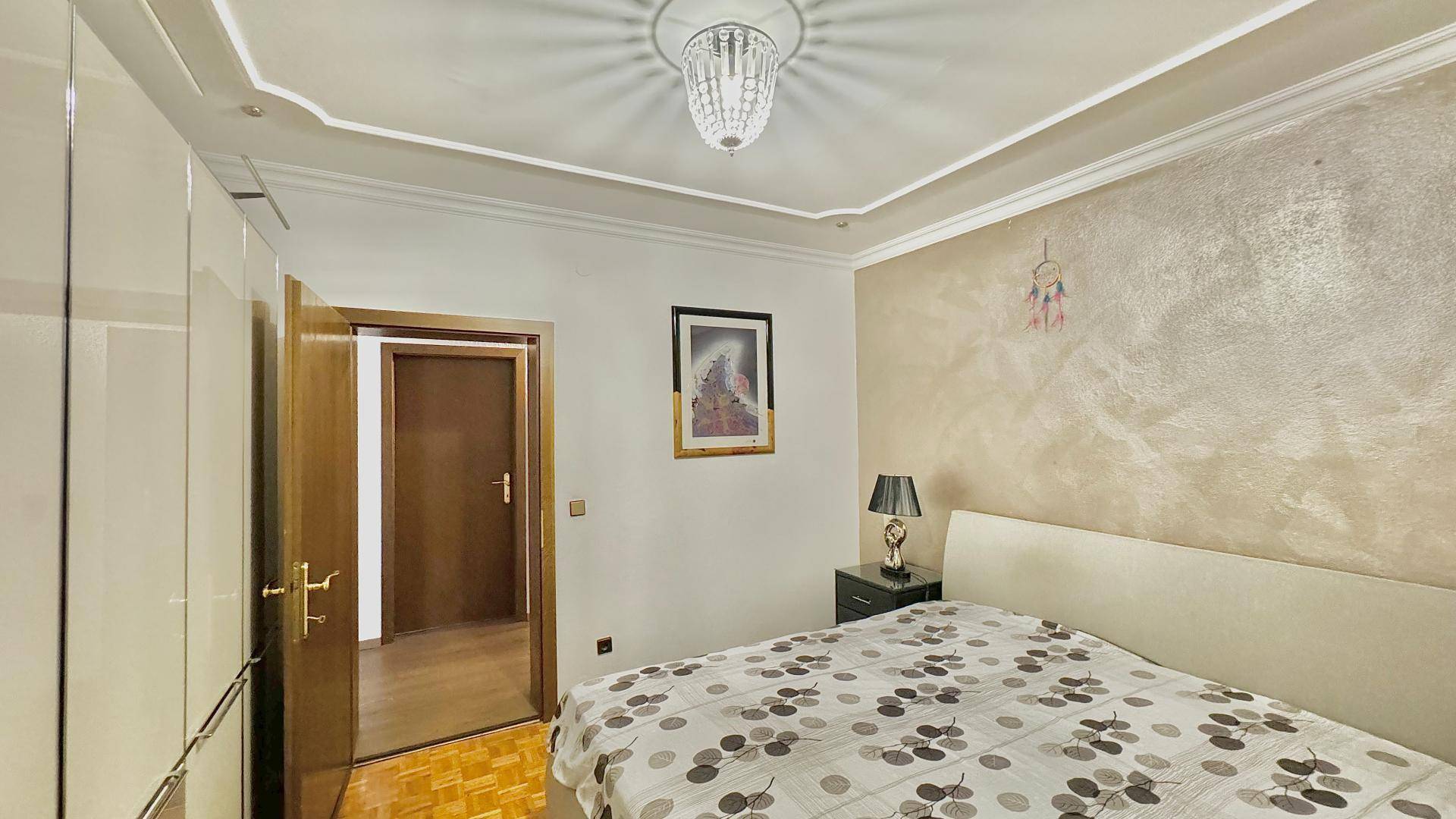 Schlafzimmer mit Doppelbett, Einbauschränken und dekorativer Wandgestaltung.