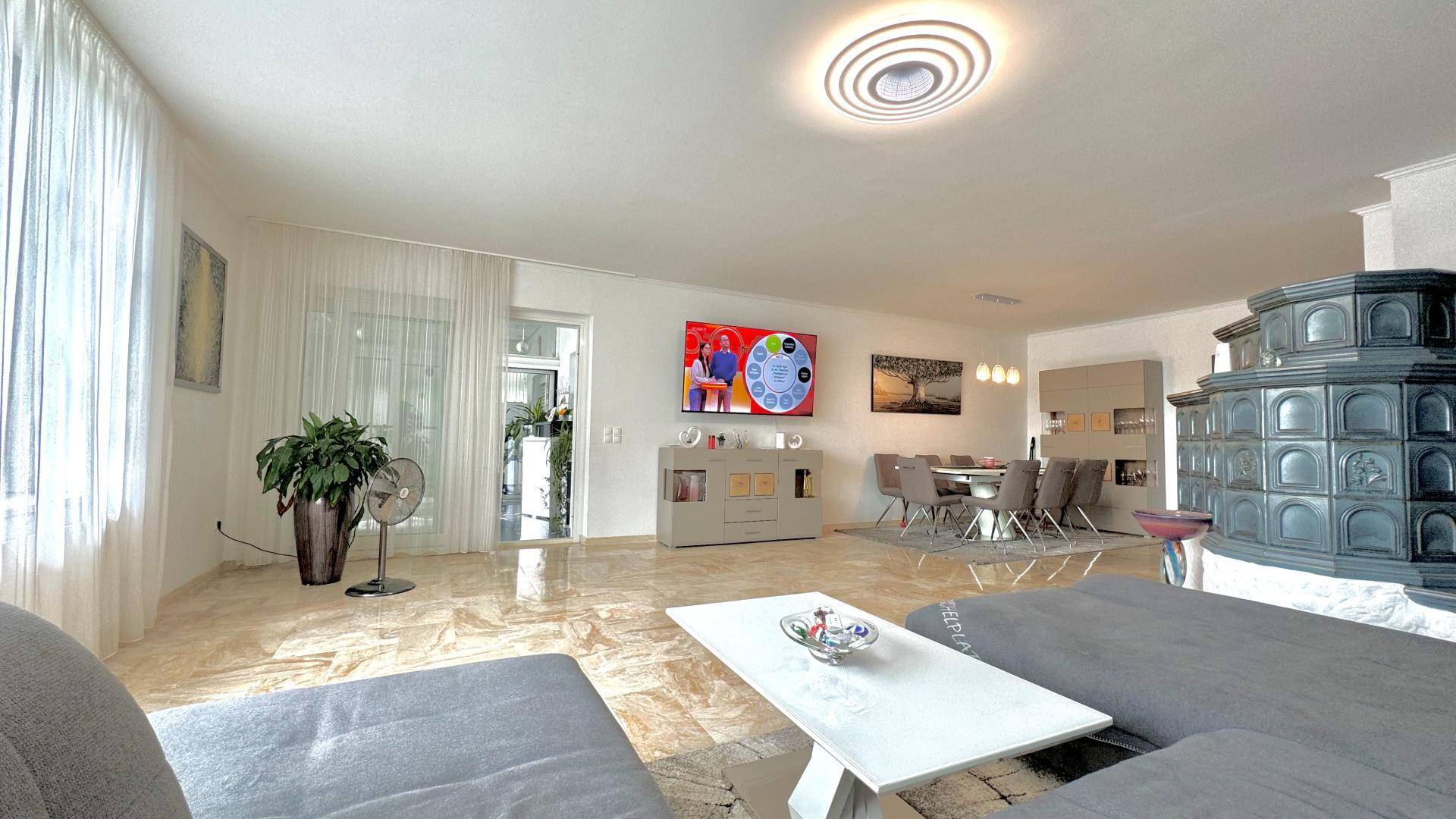 Heller Wohnbereich mit großem Sofa, Fernseher und Blick auf den Essbereich.
