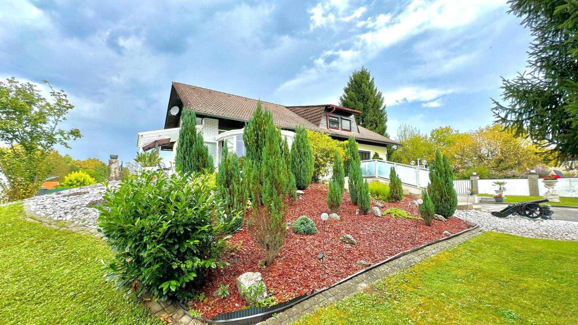 Gepflegter Garten mit Formschnittgehölzen und Bäumen, die zum Haus hinaufführen.