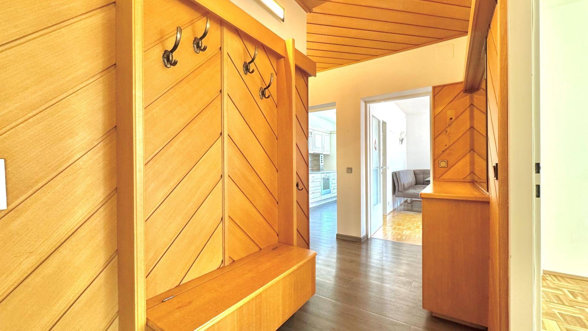 Heller Flur mit Holzvertäfelung, Garderobe und Sitzbank, führt zu weiteren Räumen.