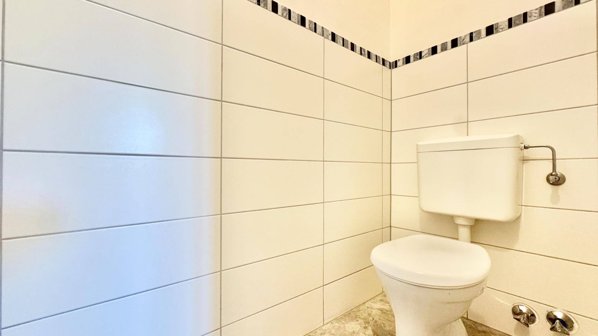 Separate Toilette mit hellen Fliesen und Standard-WC.