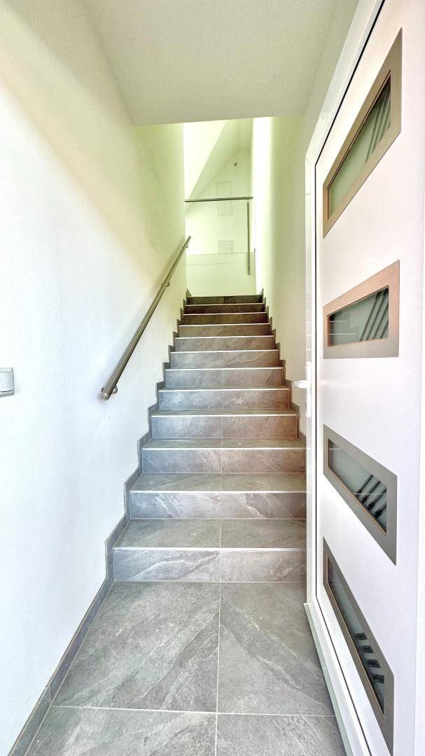 Moderner Eingangsbereich mit gefliestem Boden und Treppe, die in die oberen Stockwerke führt.