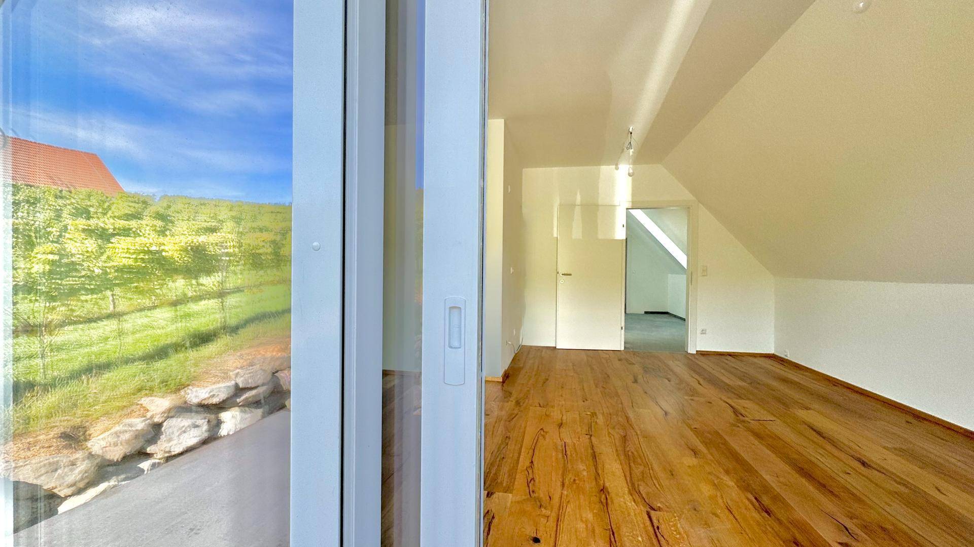 Innenansicht mit großem Fenster, das einen direkten Blick auf die sonnigen Weinberge bietet.