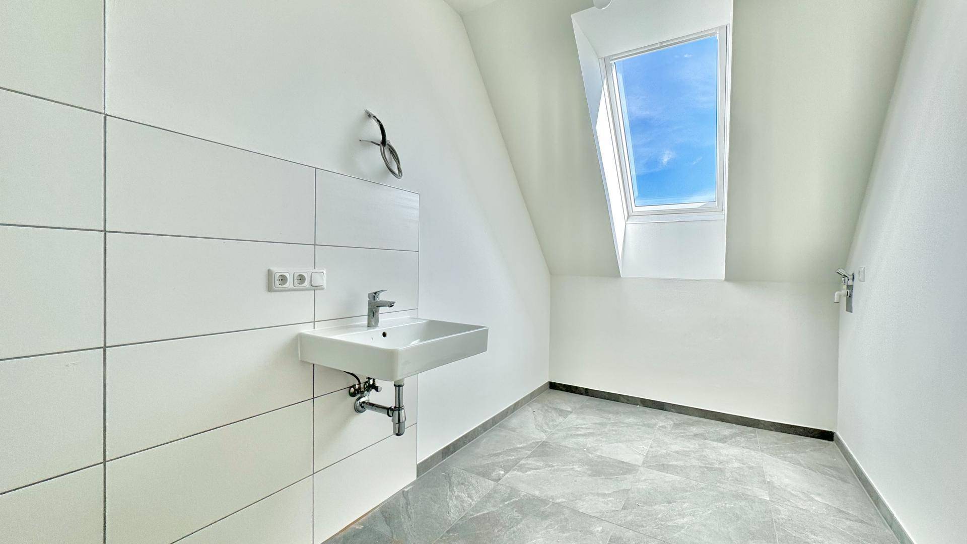 Modernes Badezimmer mit Einzelwaschbecken, weißen Fliesen und einem Oberlicht für natürliches Licht.