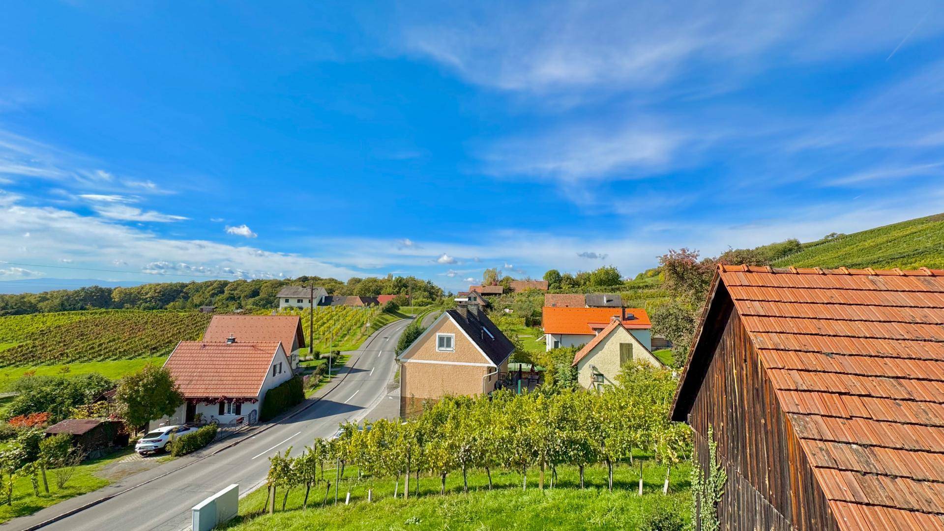 Panoramablick über ein malerisches Dorf mit Weinbergen und traditionellen Häusern unter blauem Himmel.