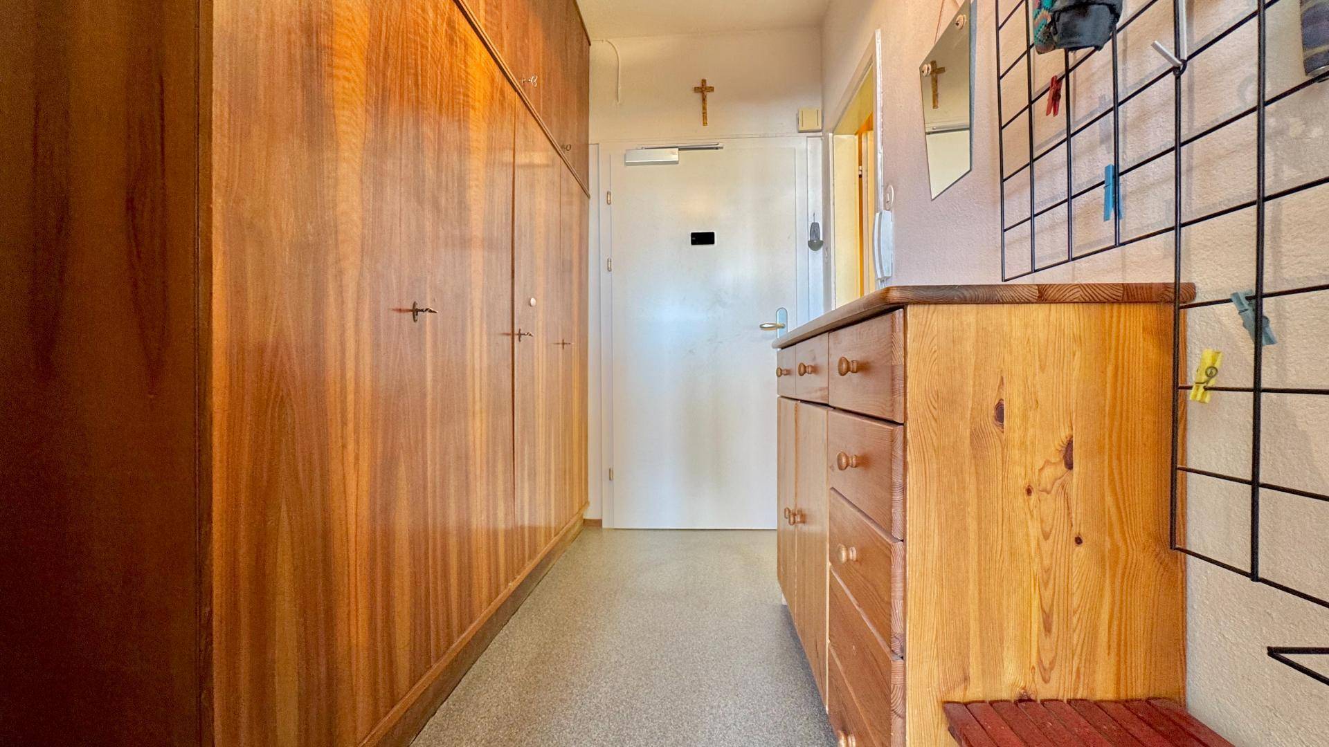 Langer Flur mit Einbauschränken aus Holz und einer Kommode, die viel Stauraum bietet.