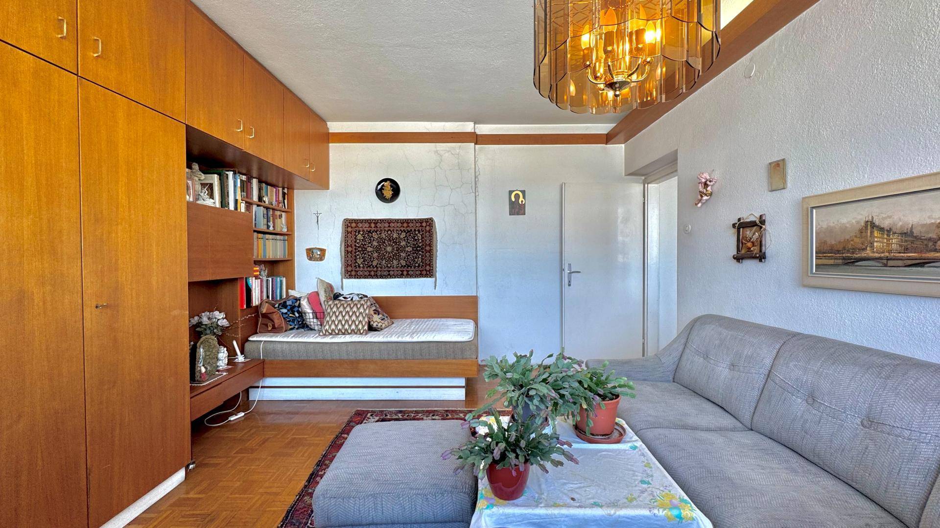 Wohnzimmer mit Tagesbett, umfangreichen Holz-Einbauschränken und einem gemütlichen Ambiente.