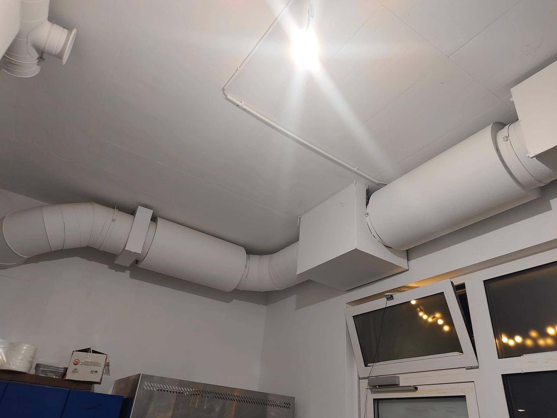 Decke mit komplexen Lüftungsrohren und Fenstern, die den Raum mit Licht versorgen.