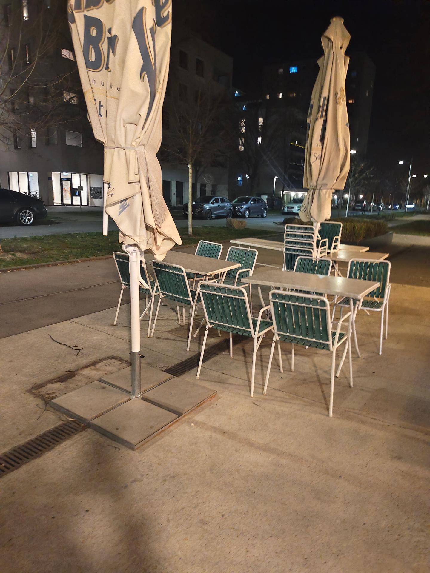Außenbereich mit Tischen und Stühlen unter großen Sonnenschirmen, bereit für Gäste.