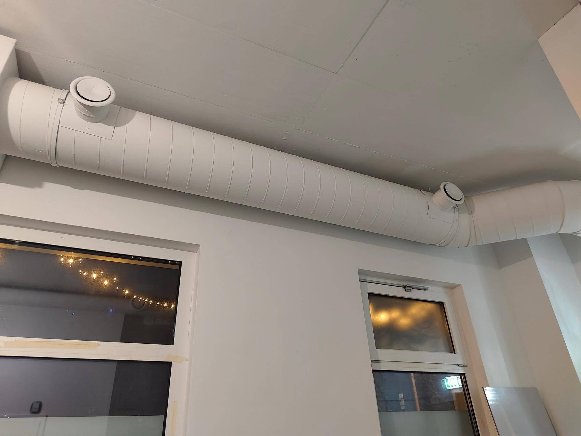 Decke mit sichtbaren Lüftungsrohren und Fenstern, die natürliches Licht hereinlassen.