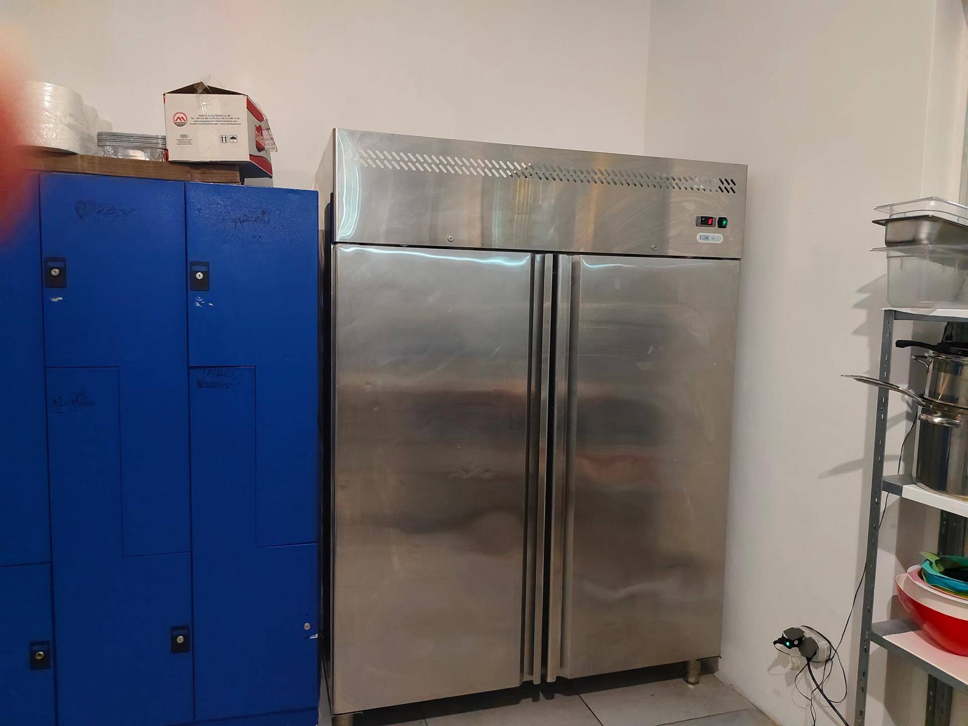 Lagerraum mit einem großen Edelstahl-Kühlschrank und blauen Spinden.