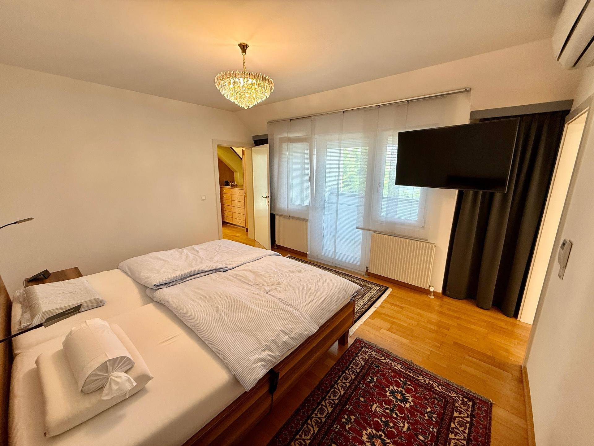Gemütliches Schlafzimmer mit Doppelbett, Parkettboden und Zugang zum Balkon.