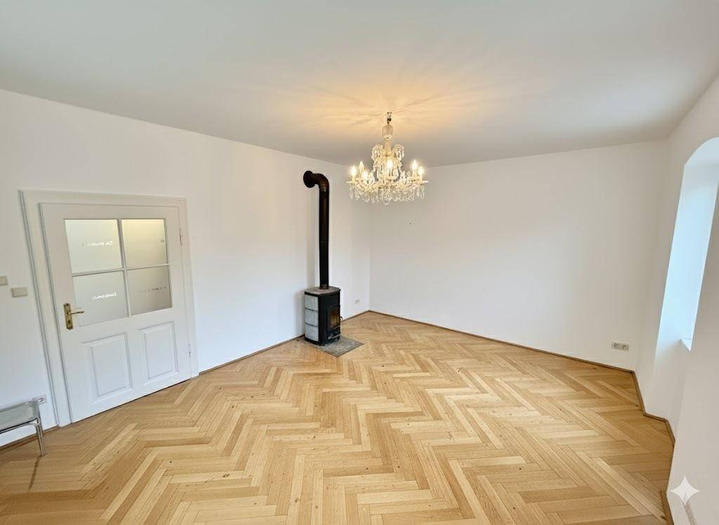 Helles Zimmer mit Fischgrätparkett und einem eleganten Kaminofen, ideal für gemütliche Abende.
