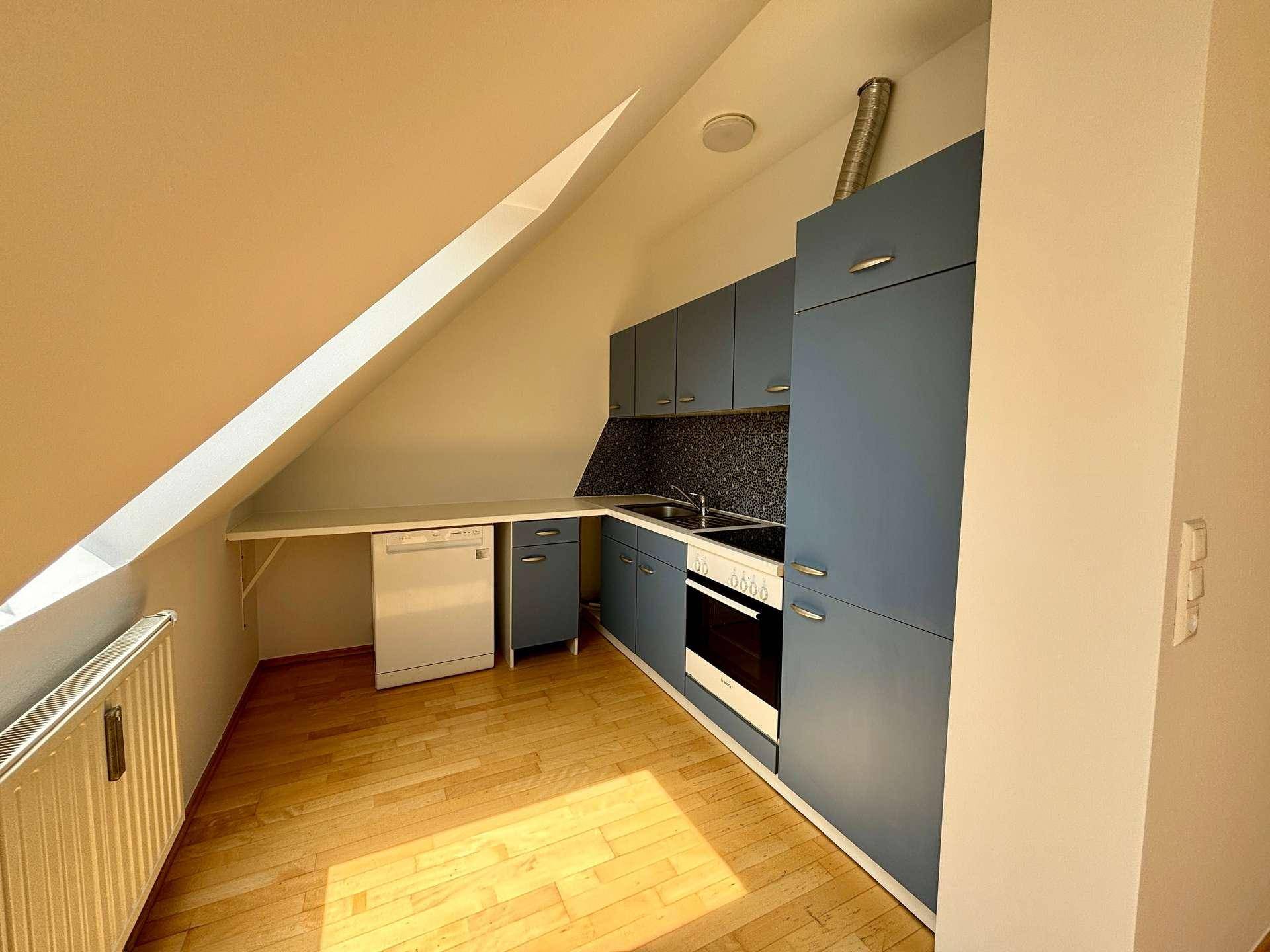 Funktionale Küche im Dachgeschoss mit blauen Schränken, integriertem Backofen und Geschirrspüler.
