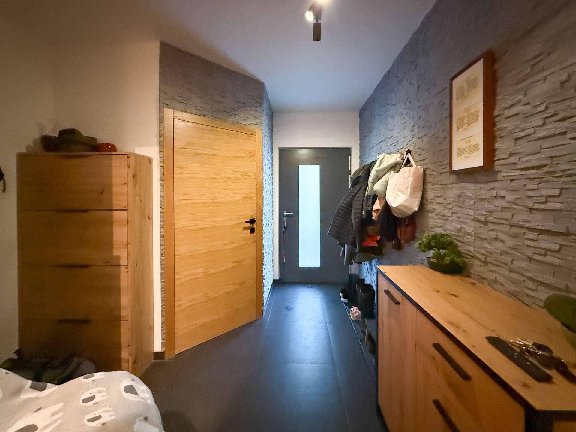 Moderner Flur mit Steinwand-Optik, Holztüren und praktischen Möbeln.