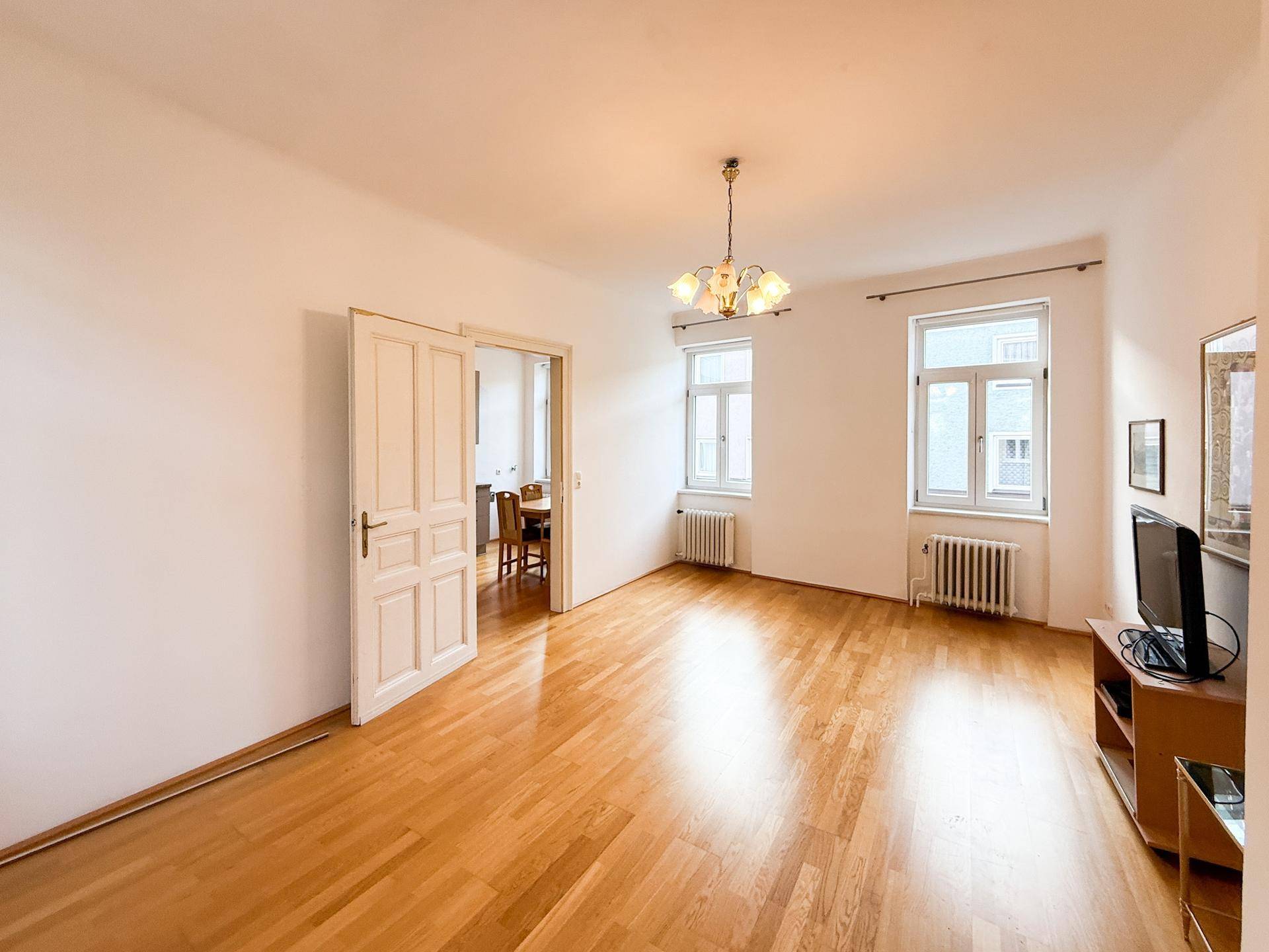 Geräumiges Wohnzimmer mit Holzboden und Blick in den angrenzenden Essbereich.