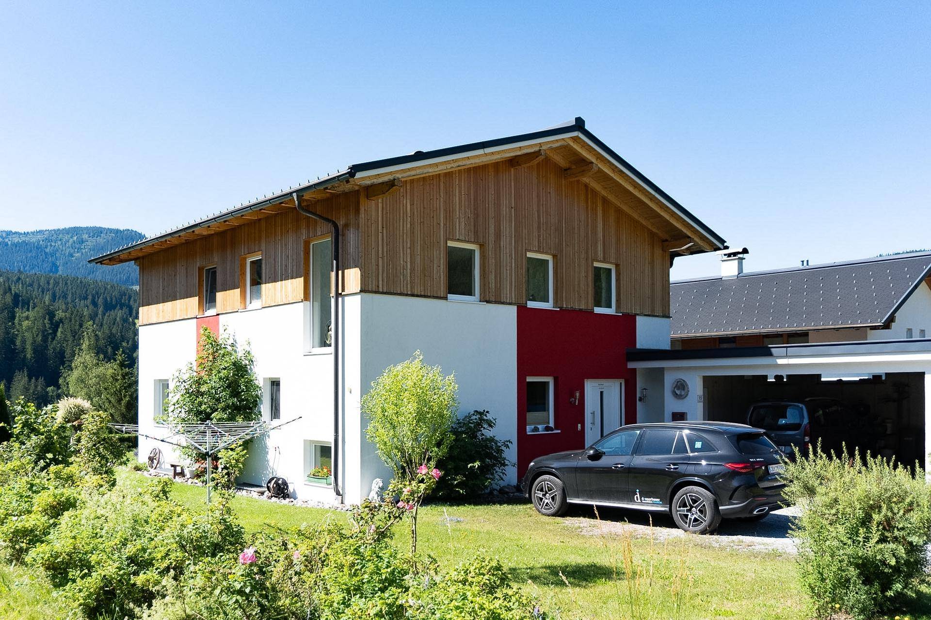 Vorderansicht des Hauses mit moderner Fassade, Carport und gepflegtem Vorgarten.