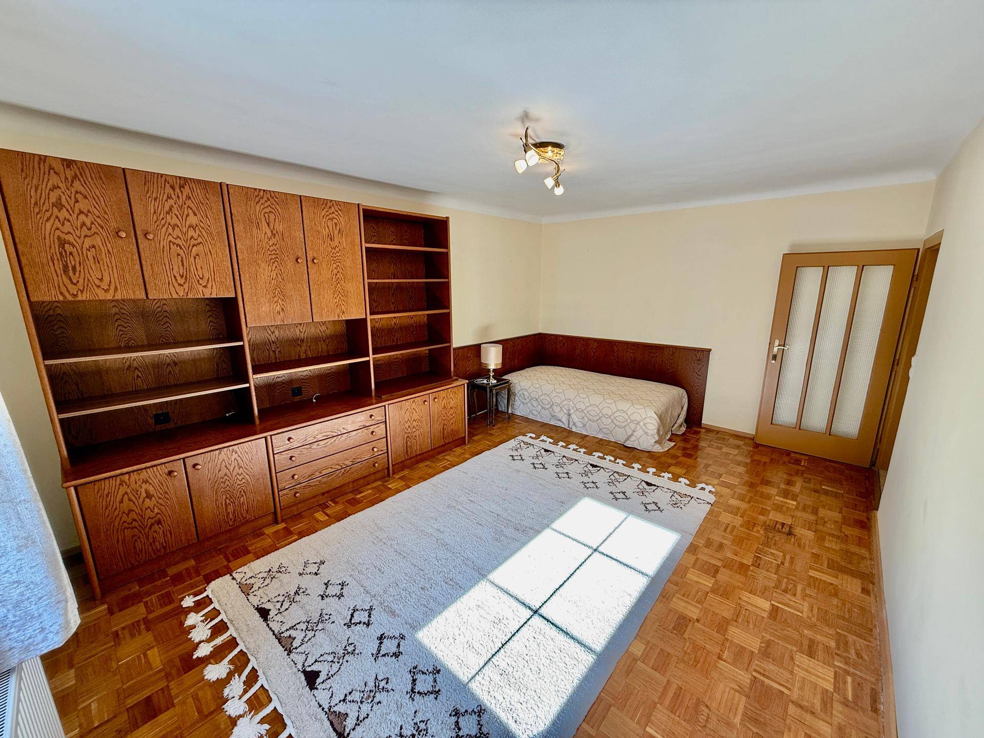 Schlafzimmer mit Parkettboden, großem Wandschrank und Einzelbett.