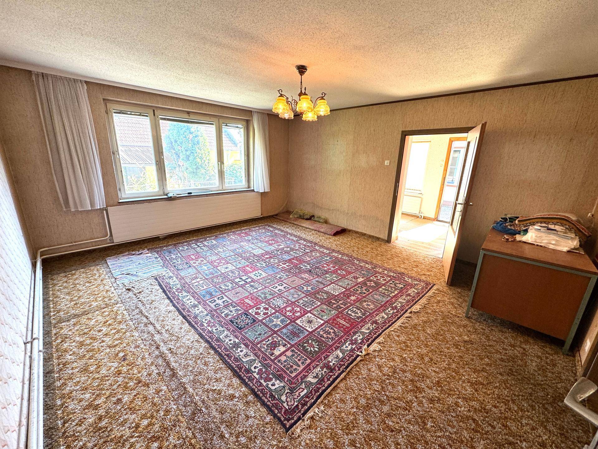 Geräumiges Zimmer mit Teppichboden, großem Orientteppich und Blick nach draußen.