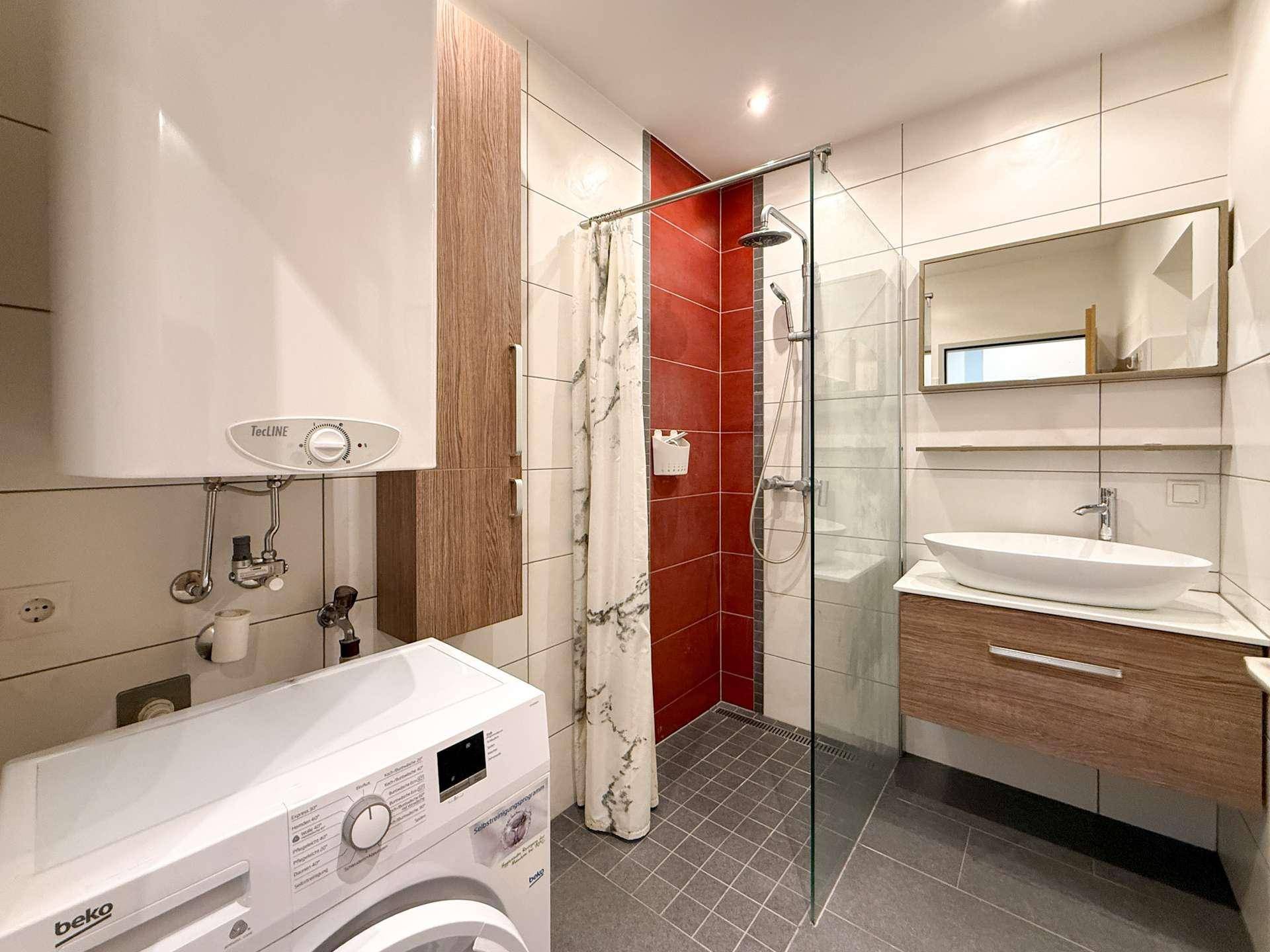 Modernes Badezimmer mit Dusche, Waschmaschine und Waschbecken mit Unterschrank.
