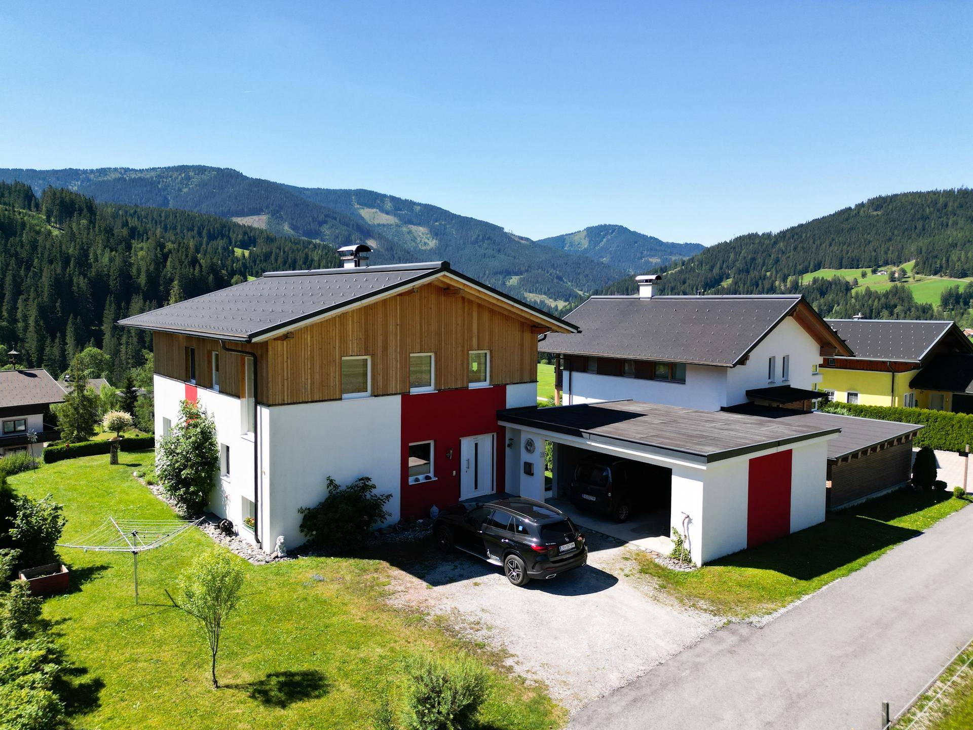 Das Haus in ländlicher Umgebung mit Carport, Vorgarten und Blick auf die umliegenden Hügel.