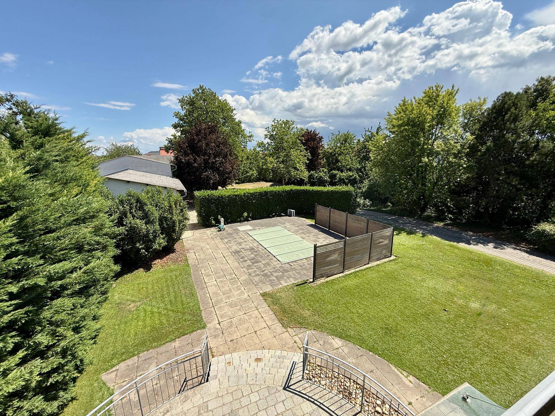 Weitläufiger Gartenbereich mit Rasenfläche, Hecken und Blick auf die Umgebung.