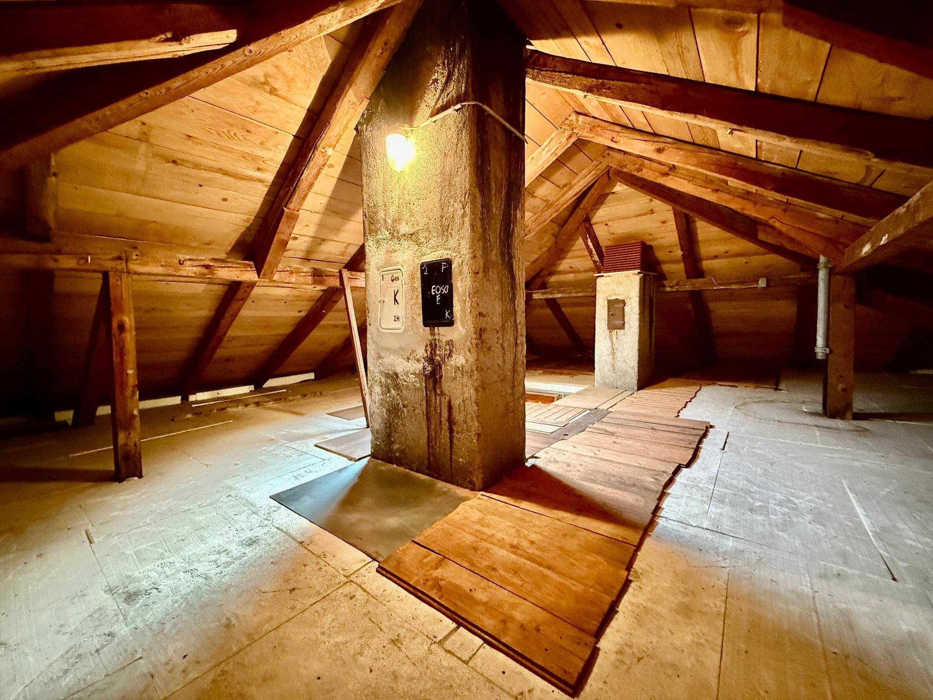 Unausgebauter Dachboden mit sichtbaren Holzbalken und viel Stauraum.