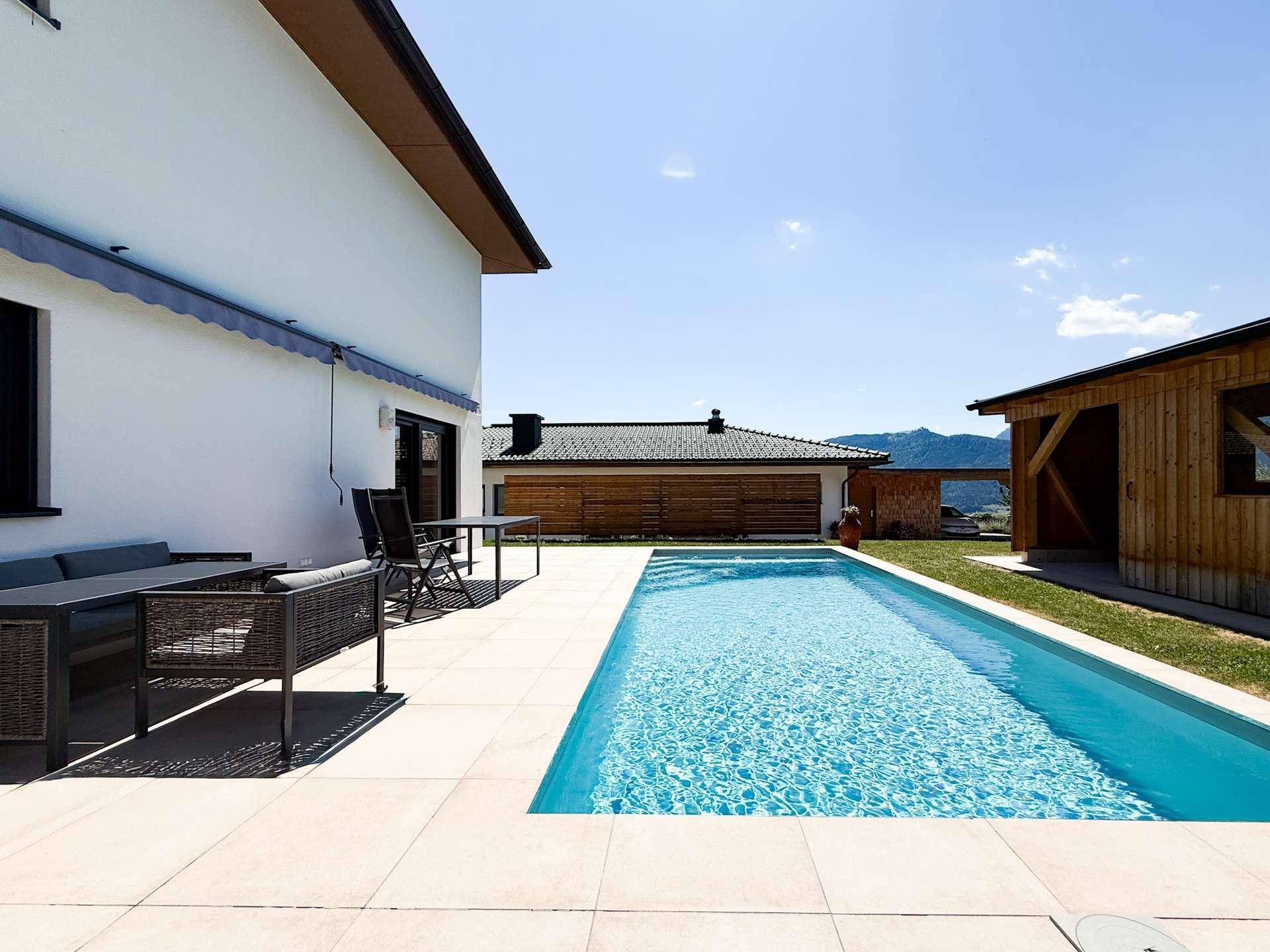 Großzügige Poolanlage mit angrenzender Terrasse und Blick auf die umliegende Landschaft.