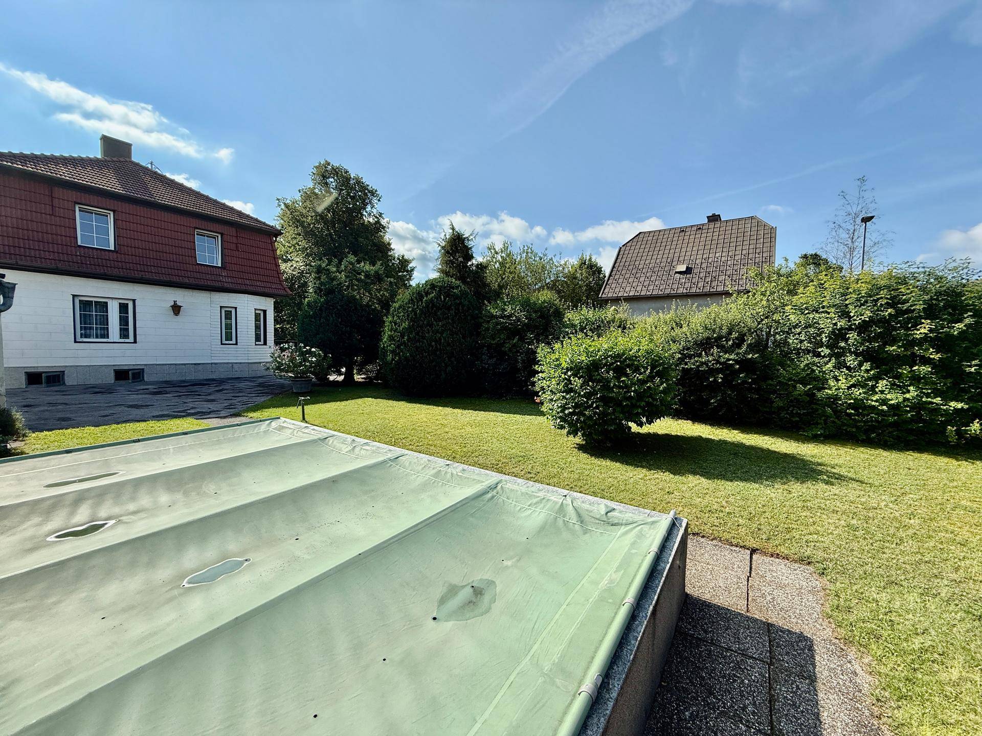 Großer Rasenbereich mit abgedecktem Pool und Blick auf das Haupthaus.