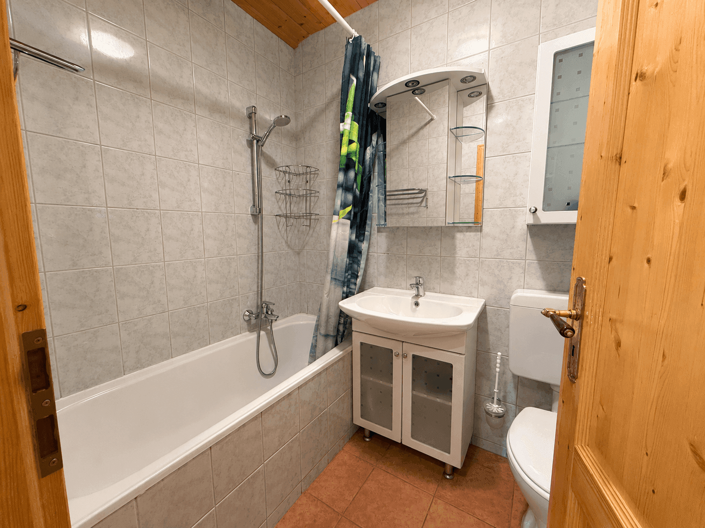 Funktionales Badezimmer mit Badewanne, Duschvorhang und hellen Fliesen.