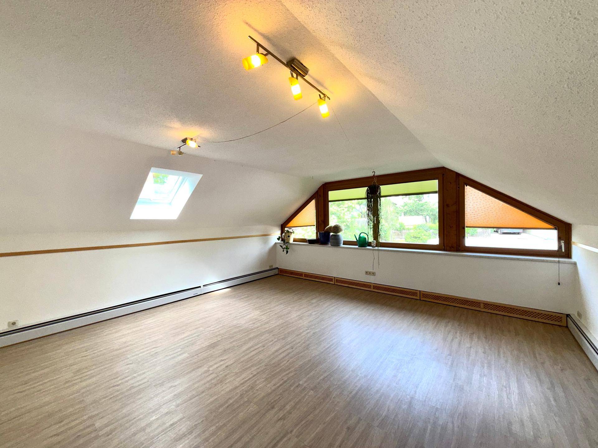 Geräumiger Dachbodenraum mit Schrägen, Dachfenster und großem Fenster, bereit zur individuellen Gestaltung.