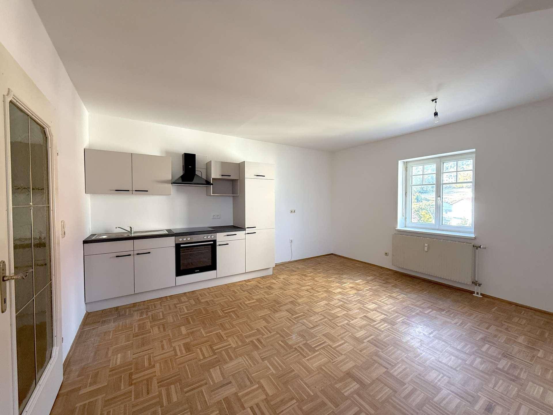 Unmöblierte Wohnküche mit neuer Einbauküche und Parkettboden, bereit zur individuellen Einrichtung.