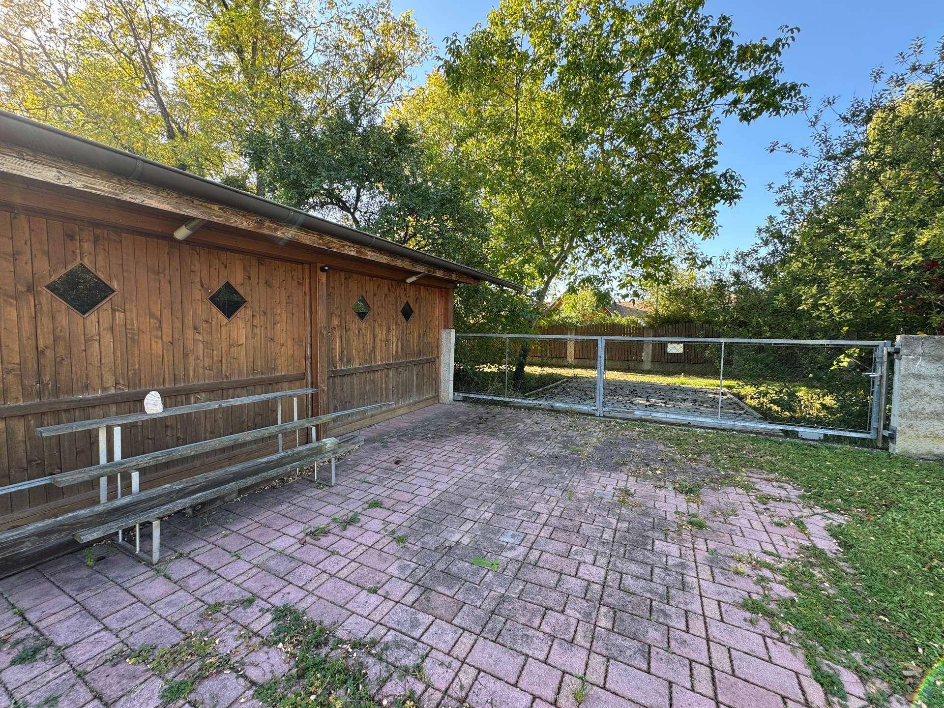 Gepflasterter Außenbereich mit Holzhütte und Zugang zum Grundstück.