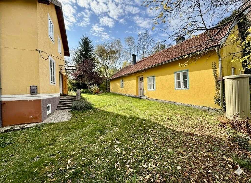 Seitenansicht des gelben Hauses mit großem, gepflegten Garten.
