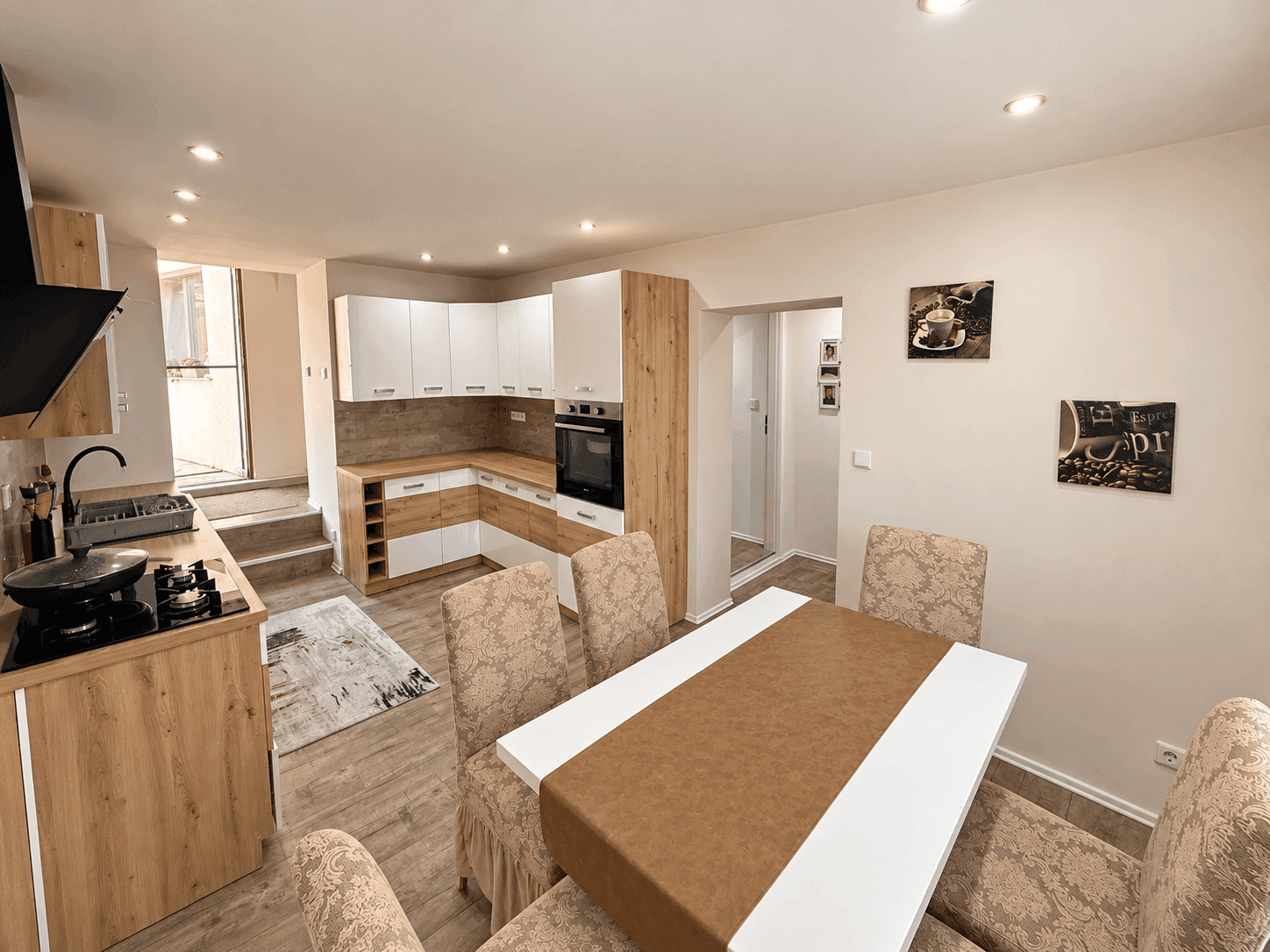 Moderne Küche mit Holz- und weißen Fronten, integrierten Geräten und Essbereich.