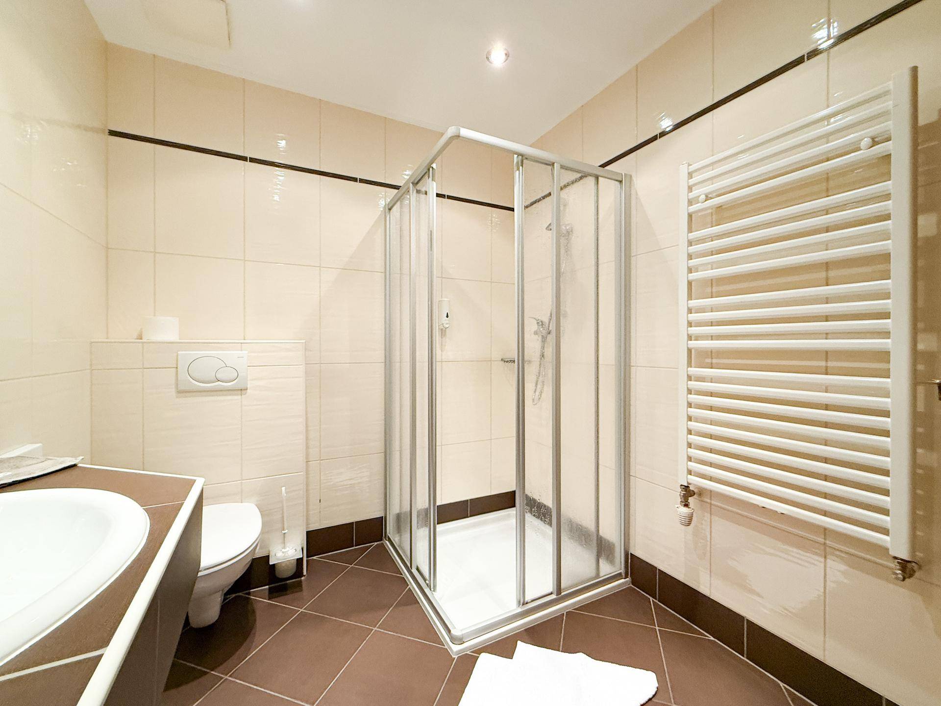 Modernes Badezimmer mit Duschkabine, Wand-WC und Handtuchheizkörper.