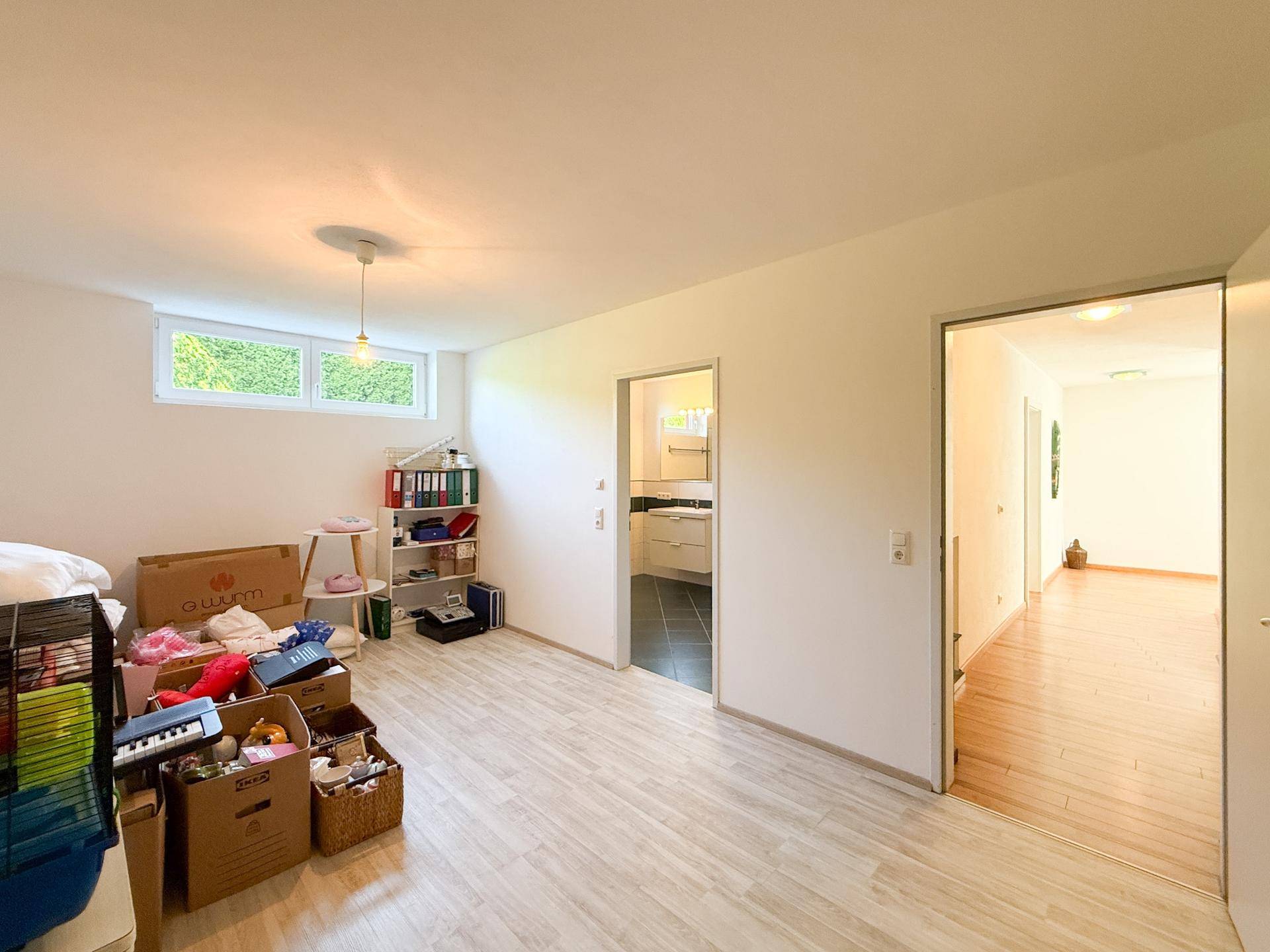 Geräumiger Kellerraum mit Fenster, Holzboden und viel Stauraum.
