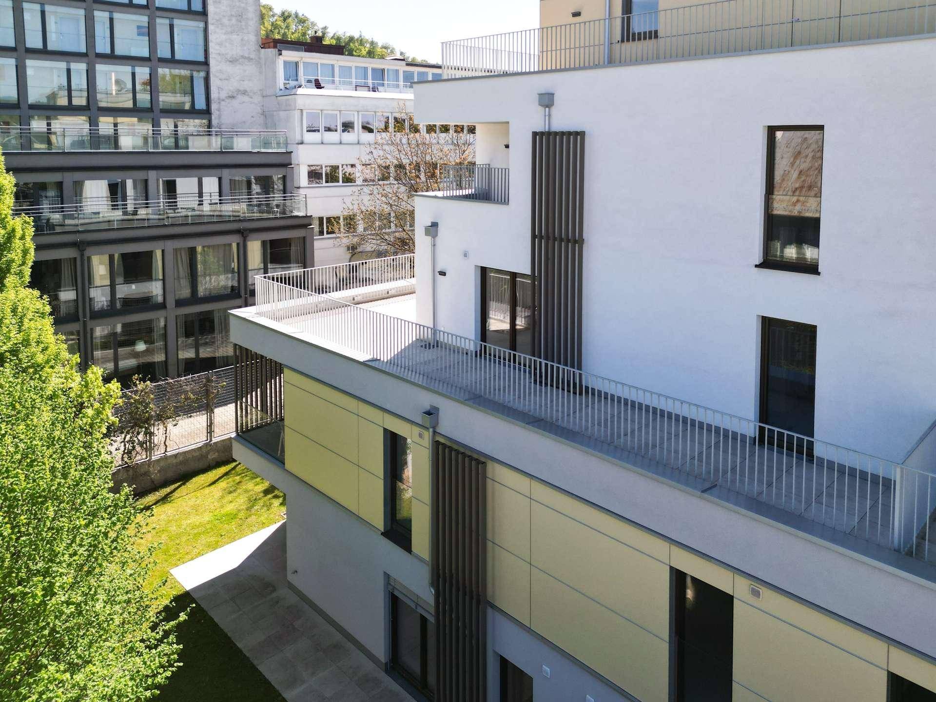 Vogelperspektive des modernen Neubaus mit Terrassen und umliegenden Grünflächen.