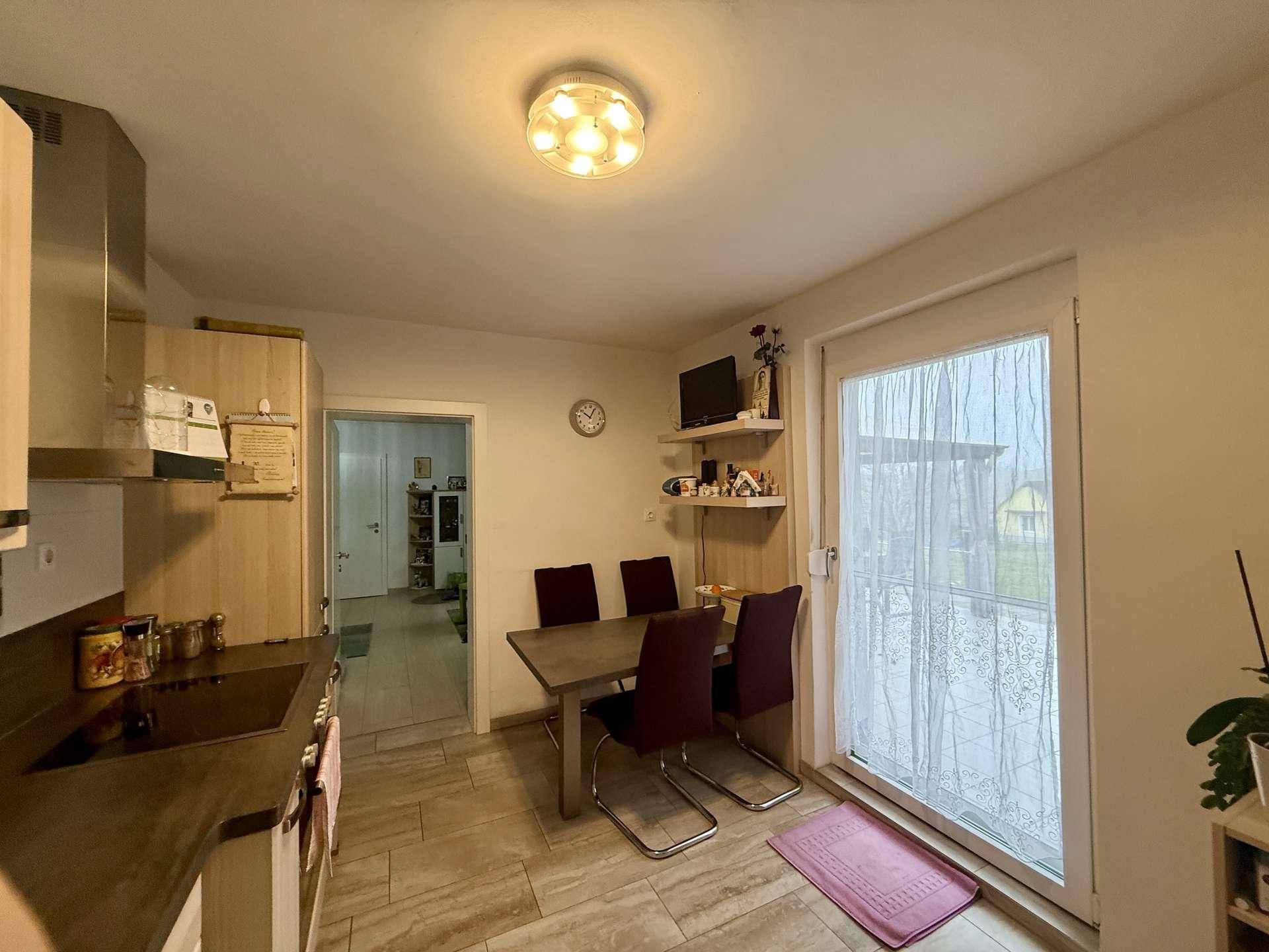 Helle Küche mit Essbereich, Fenster und Zugang zu einem Außenbereich.