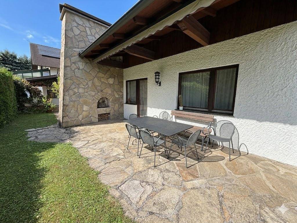 Große Terrasse mit Esstisch und Grillbereich, umgeben von Grünflächen.