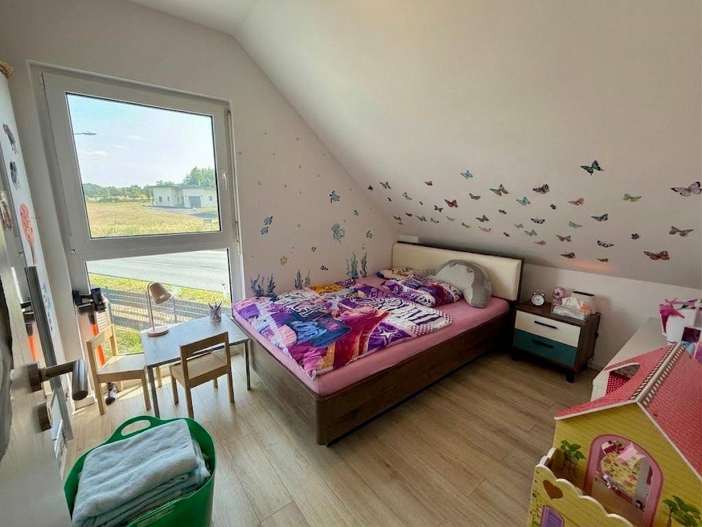 Kinderzimmer mit Bett, Schreibtisch und verspielten Schmetterlingsmotiven an der Wand.