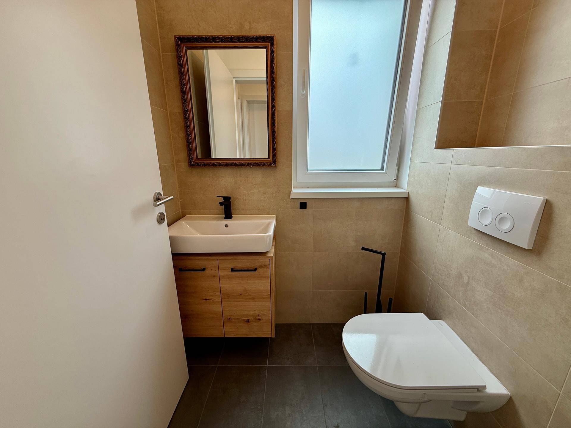 Separates Gäste-WC mit Waschtisch, wandhängendem WC und kleinem Fenster.