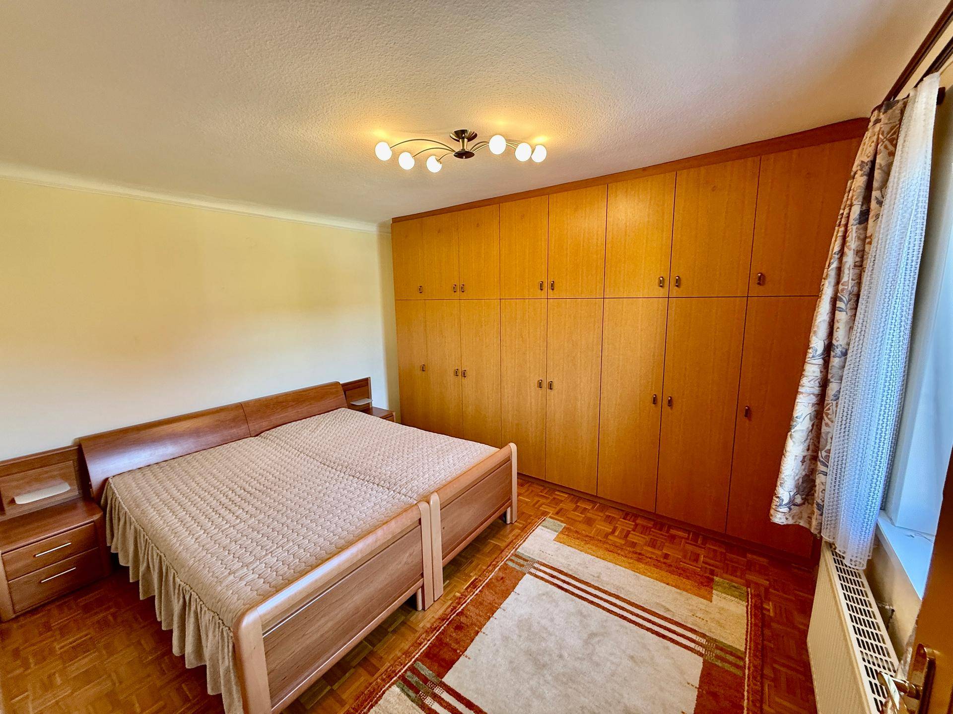 Geräumiges Schlafzimmer mit Doppelbett, Parkettboden und großen Einbauschränken.