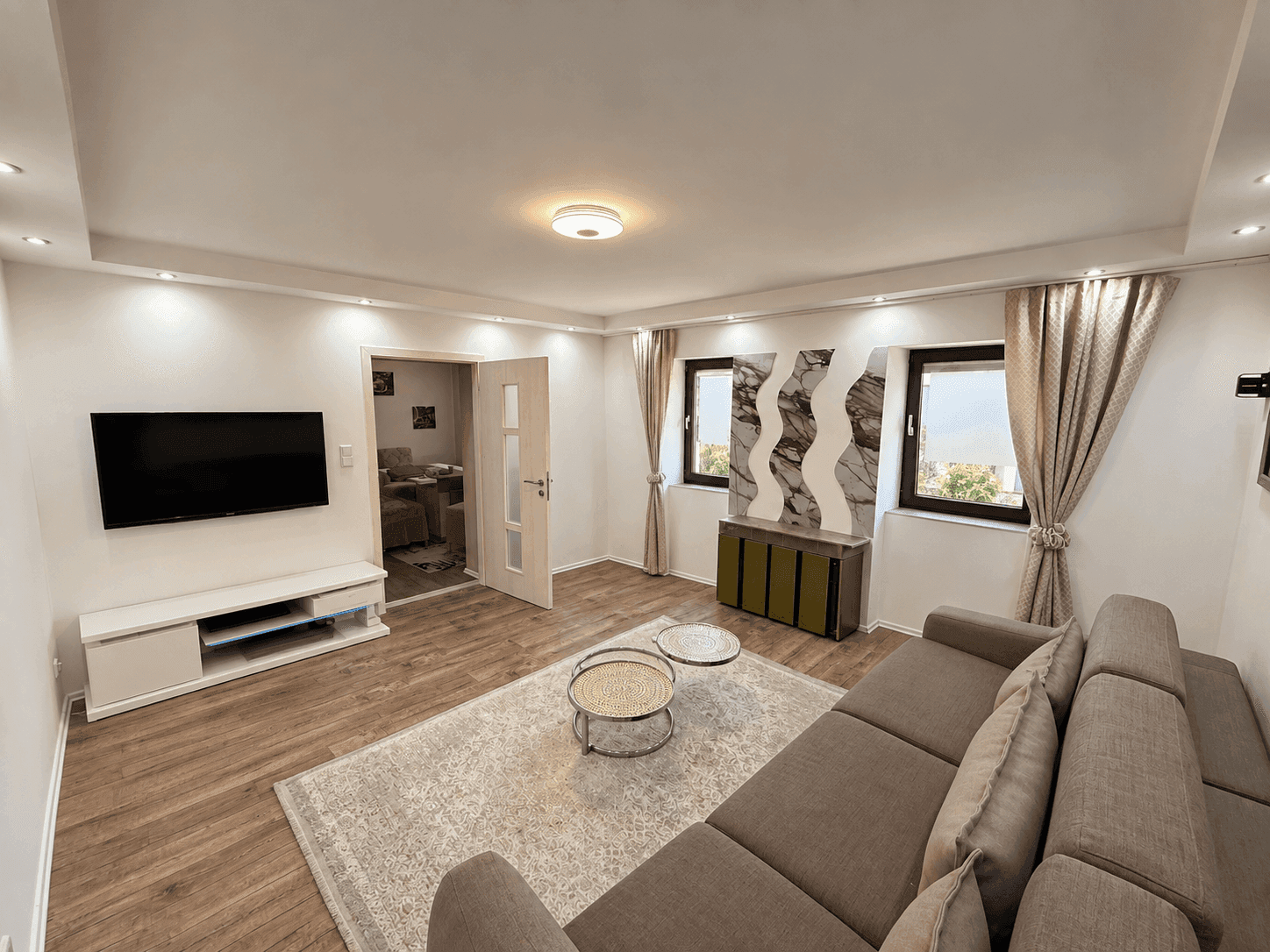 Gemütliches Wohnzimmer mit großem Sofa, modernem Dekor und Blick nach draußen.