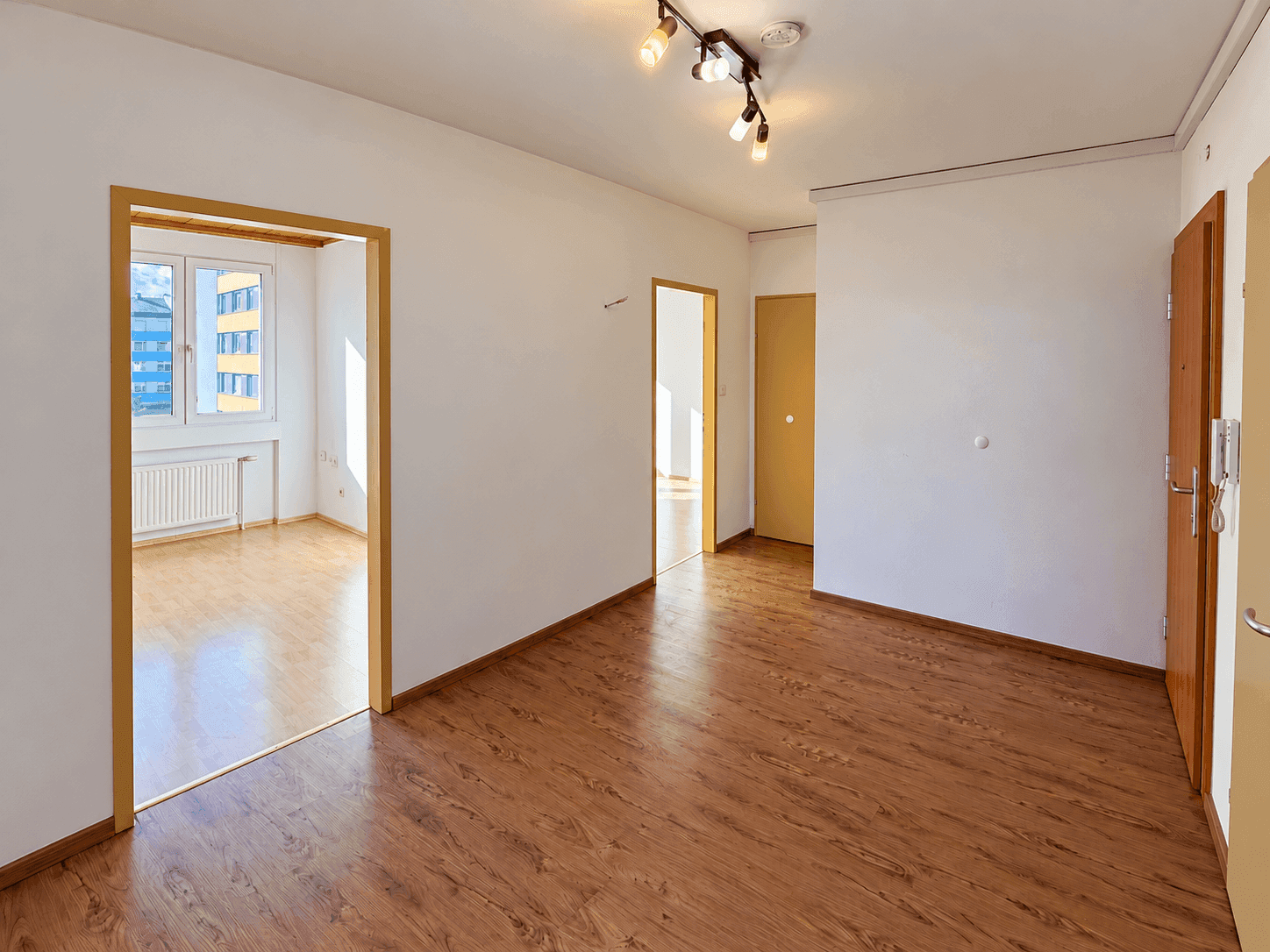 Heller Flur mit Laminatboden und Zugang zu verschiedenen Zimmern, gut beleuchtet durch Tageslicht.