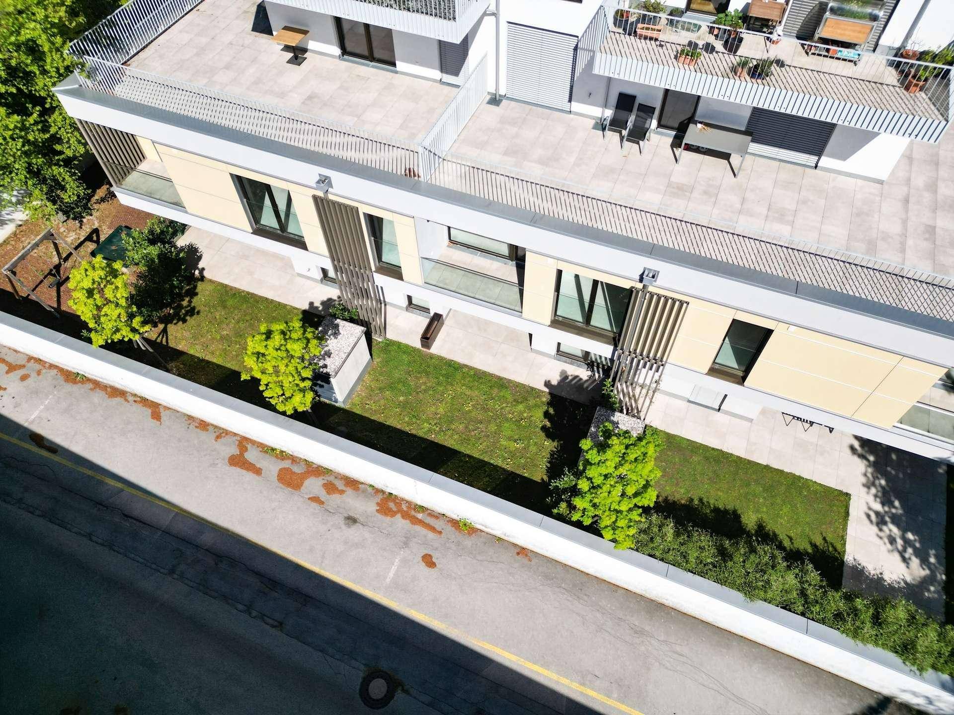 Luftaufnahme einer modernen Wohnanlage mit begrünten Gärten und Dachterrassen.
